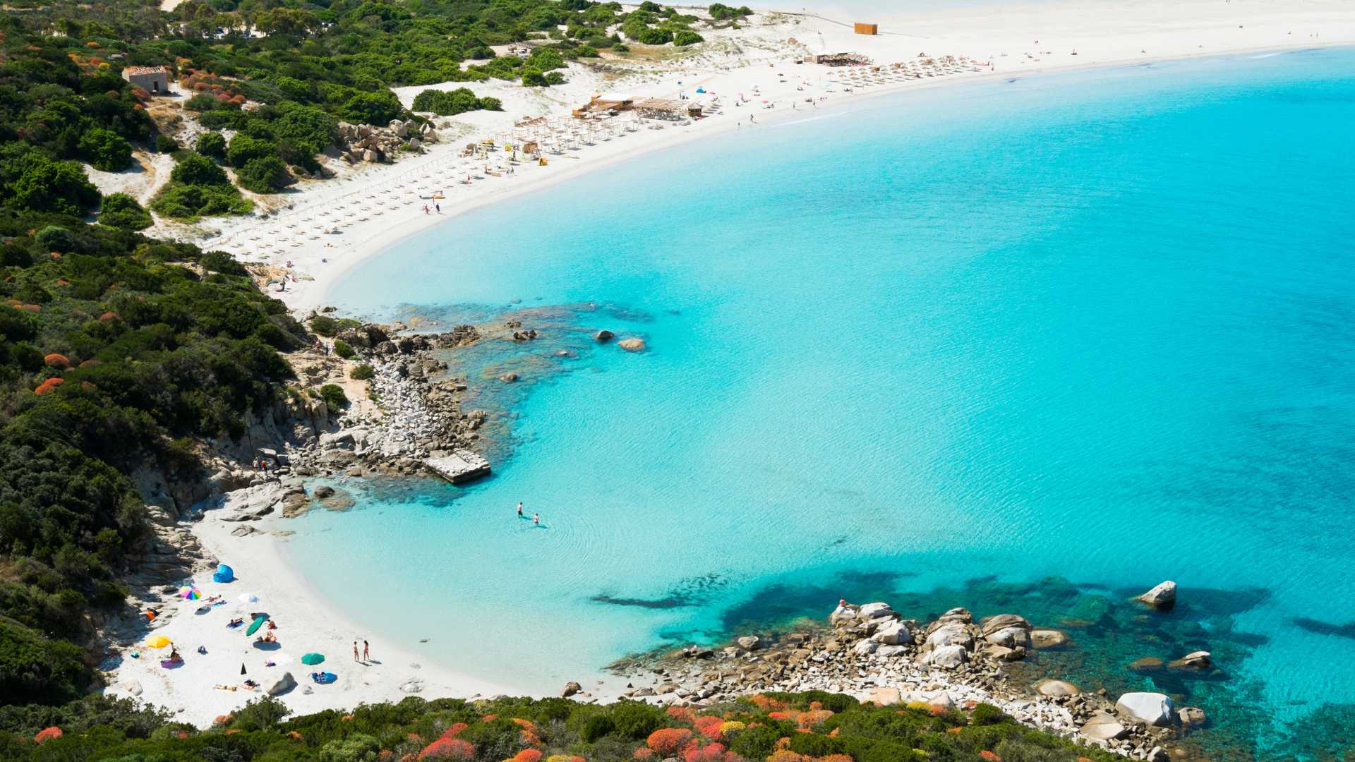 Spiaggia sarda con sabbia bianca e acque cristalline, simile a un paradiso caraibico.